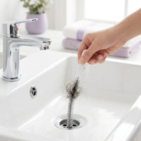 Mano retirando cabello de la coladera de un lavabo con Flowzap