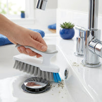Mini cepillo de Flowdeep limpiando el borde de la coladera de un lavabo