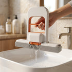 Mano tirando de la manija de Flowipe para exprimir el agua sobre un lavabo, sin mojarse las manos